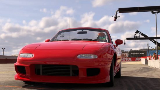 Forza Motorsport 8 release date - a red coupe on a race track. There is a driver with a helmet inside and billboards for Porsche behind the car.