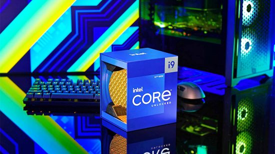 The Intel Core i9-12900K CPU sits in a box on a desk next to a keyboard, mouse, and gaming PC