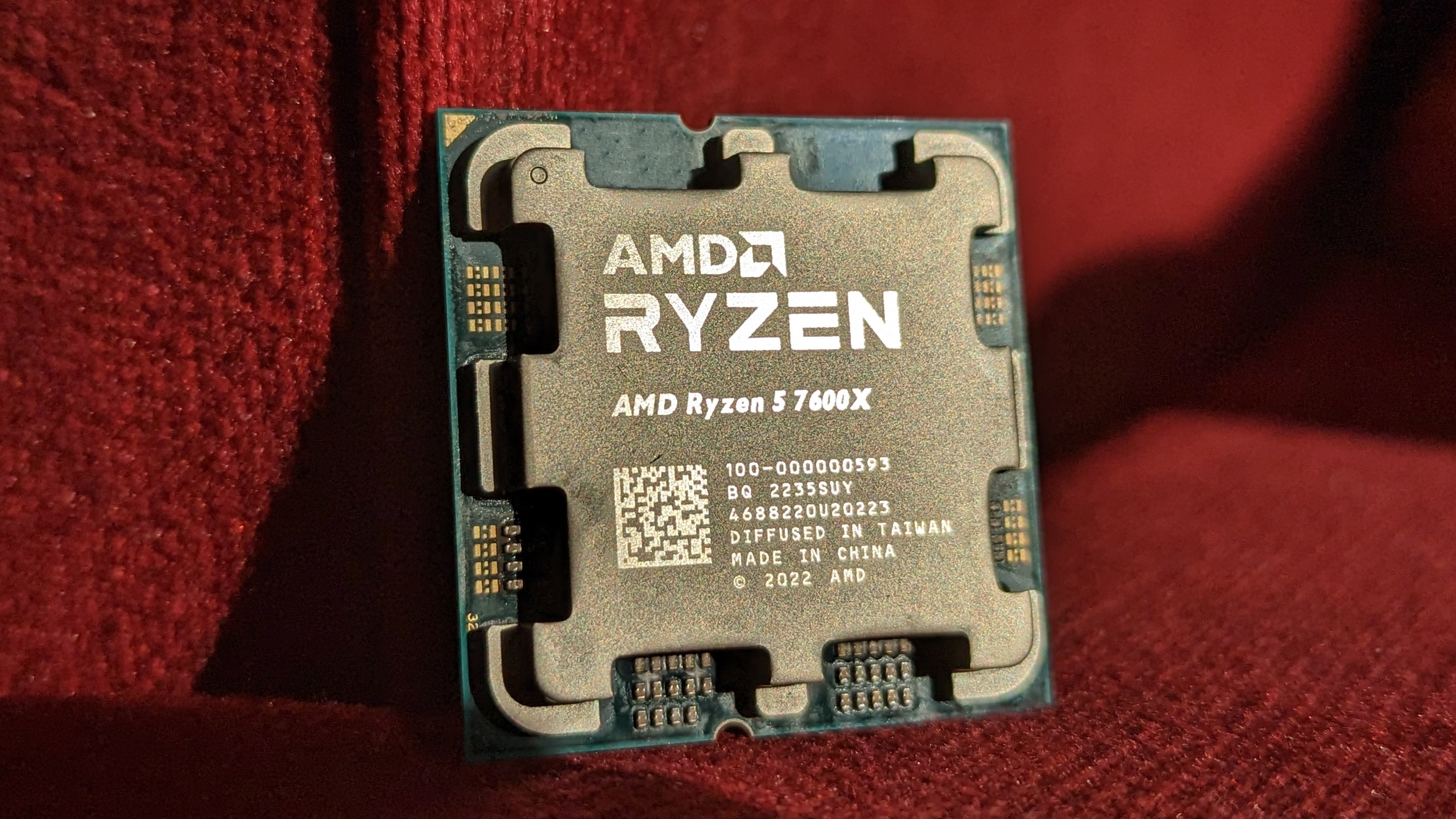 El AMD Ryzen 7600X apoyado contra un material rojo