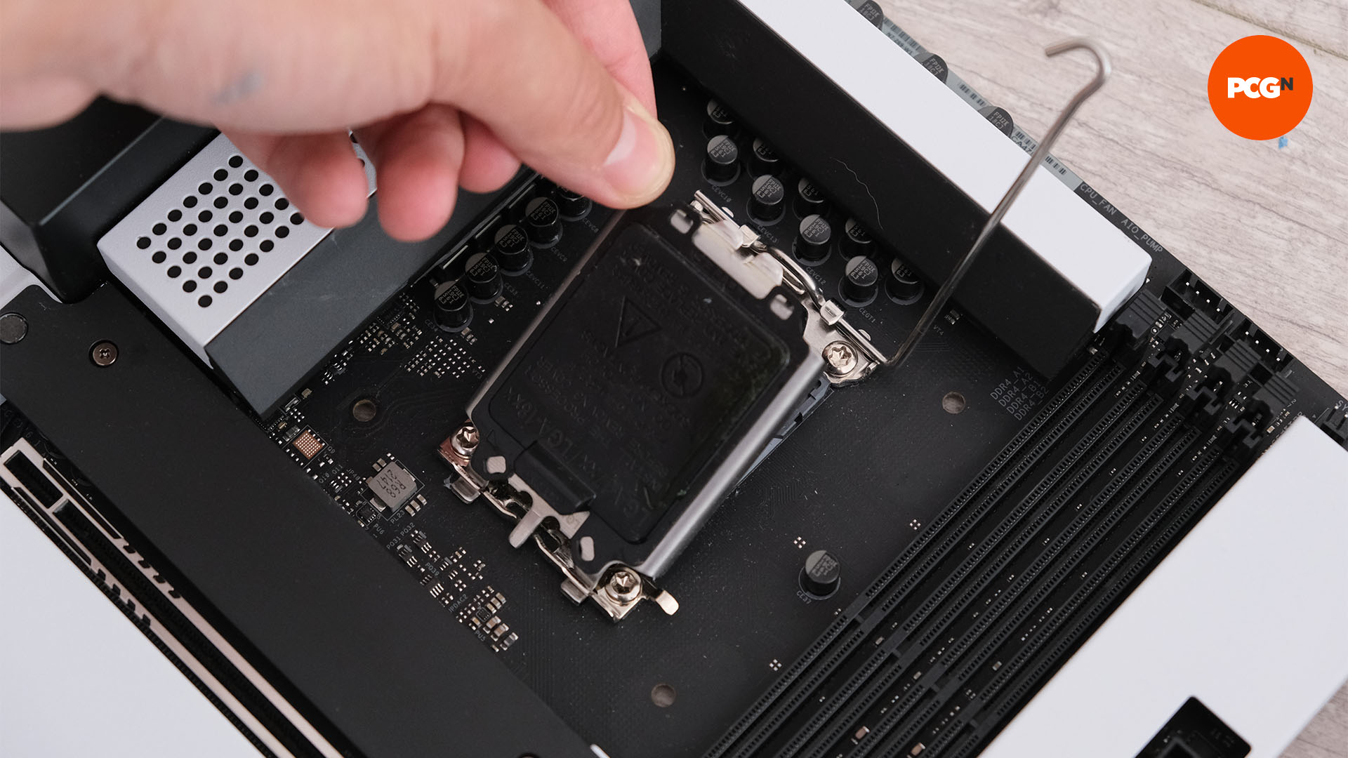 A hand pulls back the cover on the CPU port of the motherboard