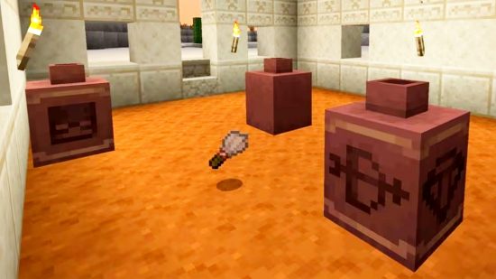 Minecraft 1.20 release date features: Minecraft archeology, showing three different pots and the archeologist's brush, on the floor of a desert building