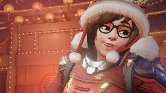 Overwatch 2 Lunar New Year: Mei wearing the red and gold Hu Tou Mao epic skin, which features a rabbit eared winter cap with white pompoms on the ends of the chin ties