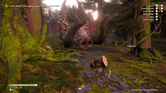Wild Hearts crossplay - a hunter is fighting a giant boar covered in moss in the overgrown jungle near an abandoned shrine. A small robot, known as a Tsukomo, is helping.