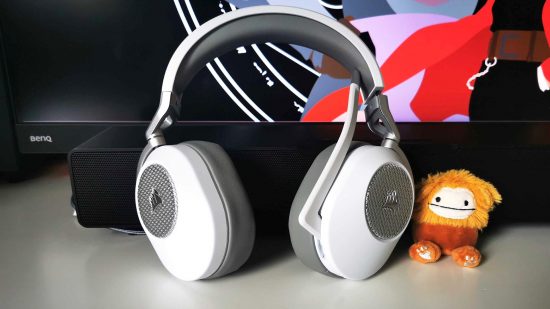 Corsair HS65 review: White gaming headset on white desk with little bigfoot plush on right