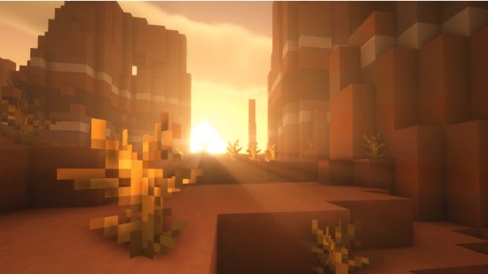 Minecraft seeds: the sun shines over the horizon in a Minecraft seed with a badlands biome, a dead bush sits in the foreground