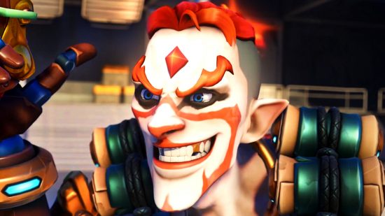 Overwatch 2 reworks - Junkrat, wearing white face paint and with his hair dyed orange, grins as he holds up a detonator