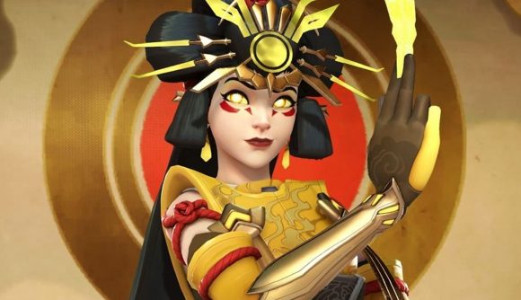 Overwatch 2 tier list: Kiriko as featured in her Amaterasu legendary skin as part of the Overwatch 2 season 3 theme of Asian mythology, wearing an elaborate headdress in imitation of the sun and holding a golden talisman before her.