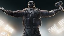 Rainbow Six Siege Year 8 update finally ends reload frustrations: A man wearing a gas mask and combat gear reaches out his arms holding a hage hammer in the right one