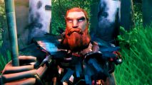 Valheim building update - a character with a hefty ginger beard standing in a forest, wearing a crow-feather cloak and holding up a torch