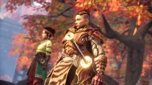 Wild Hearts microtransactions: A warrior with ornate red and gold armour and a massive odachi at his side stands beside a young woman blacksmith beneath the shade of a tree whose leaves have turned to red and yellow