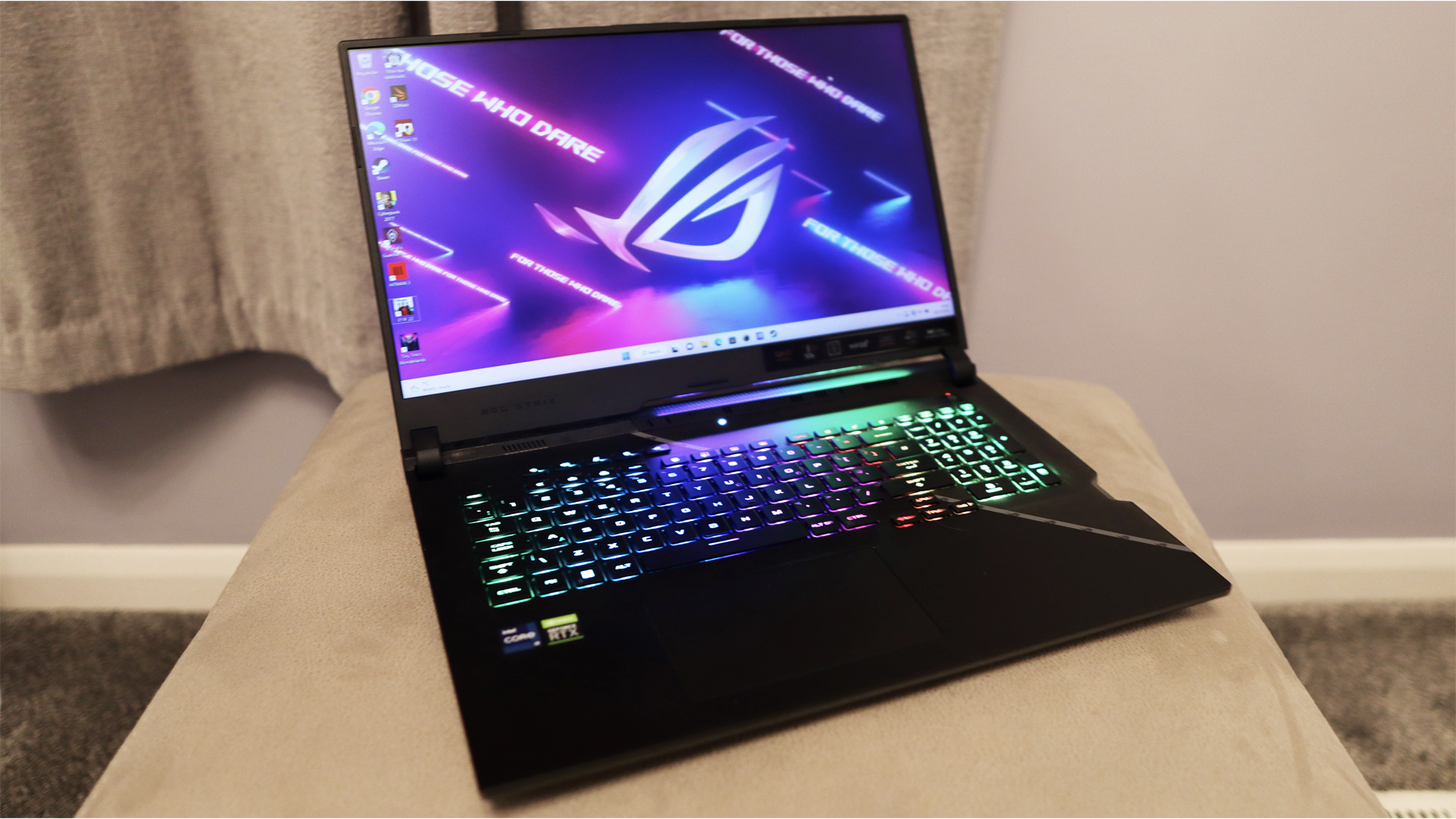 Ulasan Asus ROG Strix Scar 17: Laptop gaming diletakkan di atas dudukan krem, keyboard RGB-nya bersinar terang