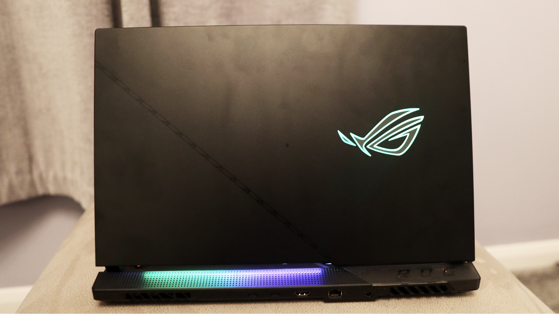 Ulasan Asus ROG Strix Scar 17: Laptop gaming diletakkan di atas dudukan krem, sasis plastiknya diterangi oleh logo RGB