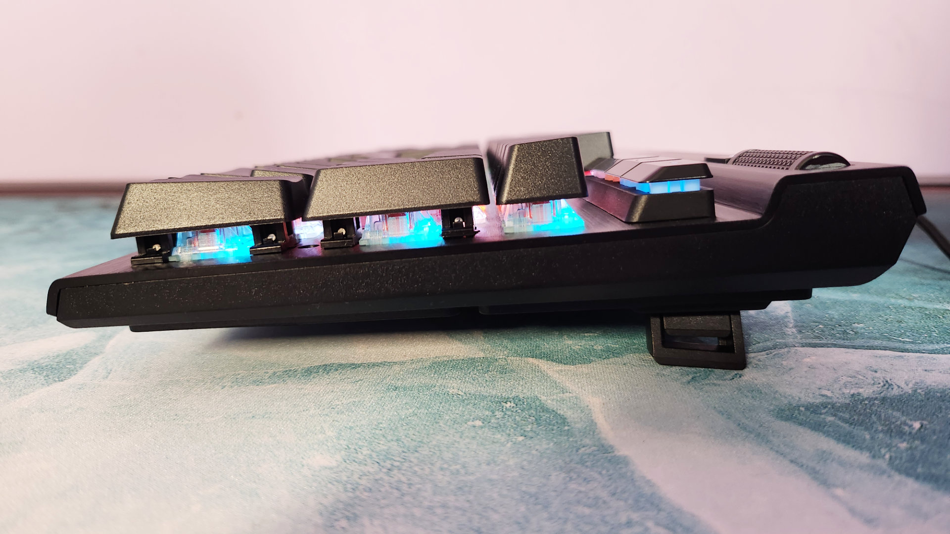 Corsair K70 RGB Pro review: A side view of a gaming keyboard, showcasing its retractable feet and RGB lighting