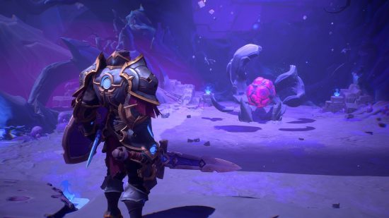 A man in hulking grey armour stands in a cavern before a huge purple ball