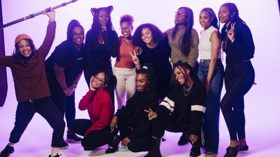 A group of black women stand in a photoshoot area posing for a picture