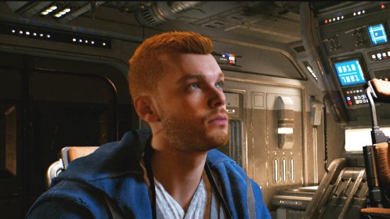 A man with a short, neat haircut sits in the cockpit of a spaceship.