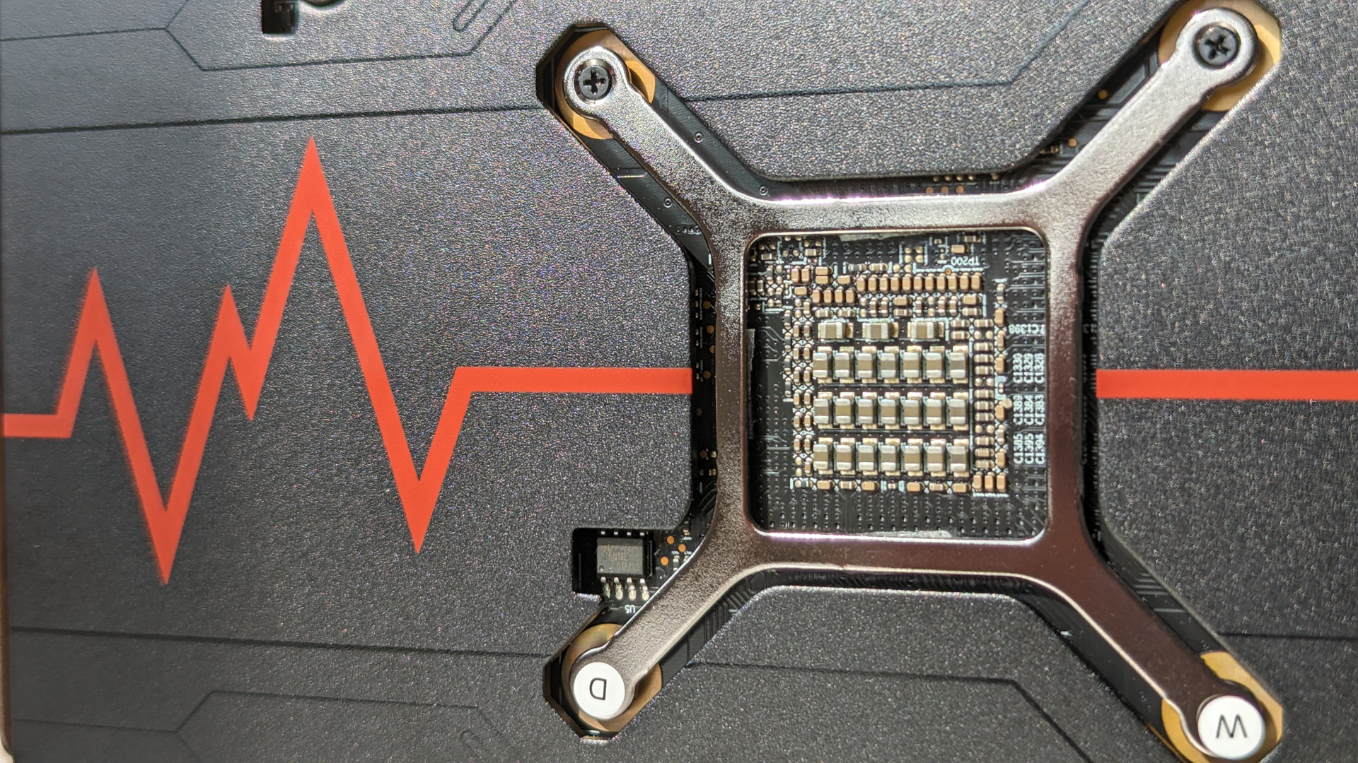Revisión de AMD Radeon RX 7600: un primer plano de la parte posterior de la tarjeta gráfica, con un gráfico de pulso rojo en la placa posterior y un soporte plateado expuesto