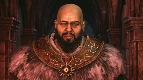 A bald man with a beard, wearing furs and a huge necklace stares at the camera.