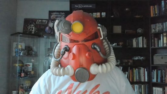 Fallout creator praises Bethesda for “revitalising” the series: a man in an office wearing a red power armour helmet, with game development tat behind him
