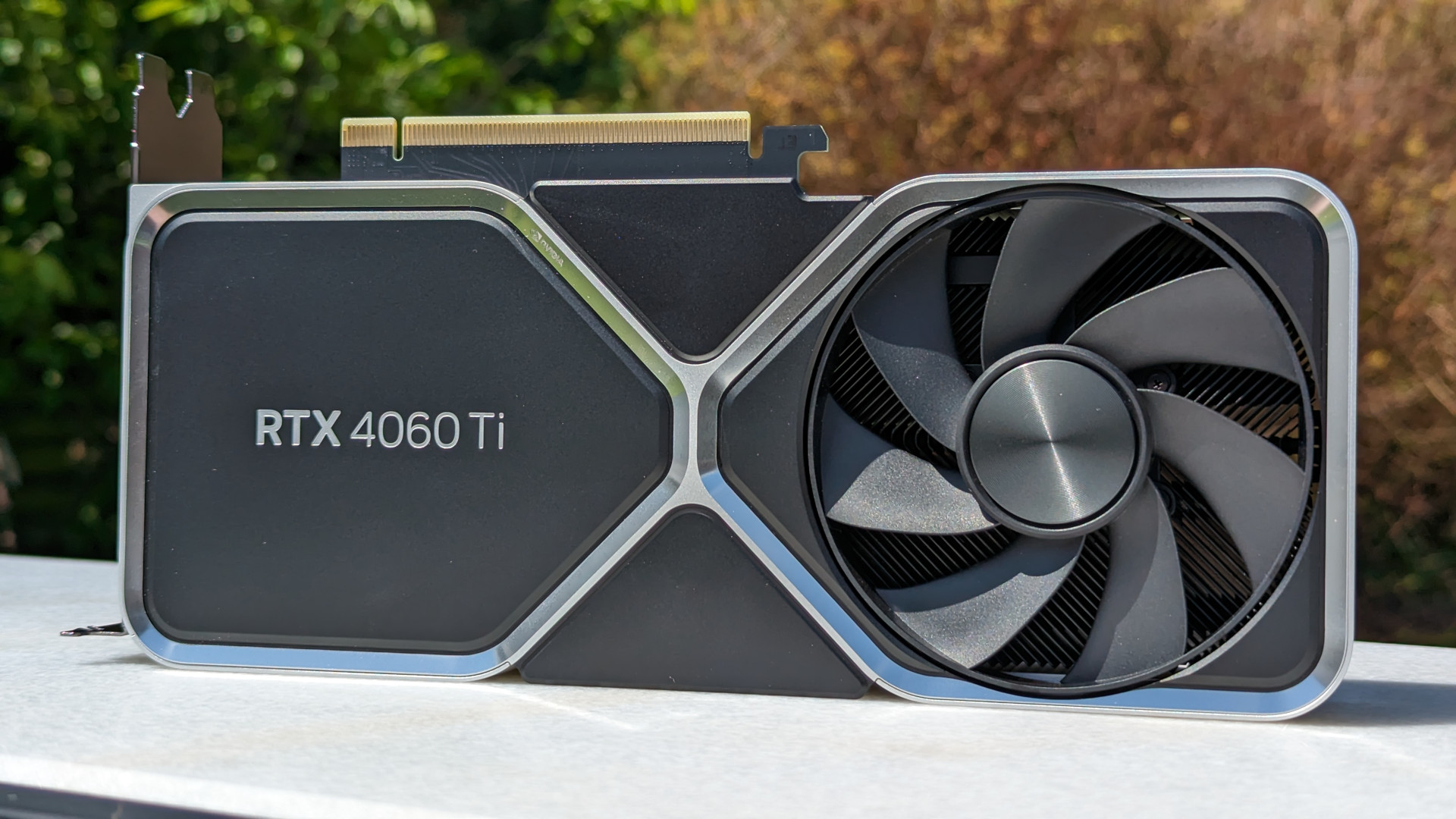 Nvidia GeForce RTX 4060 Ti 8GB review: The graphics card atop a white surface, against a nature-themed backdrop
