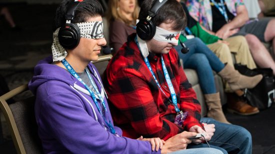 SGDQ 2023 - two speedrunners sit side-by-side wearing blindfolds, sharing a controller between them.