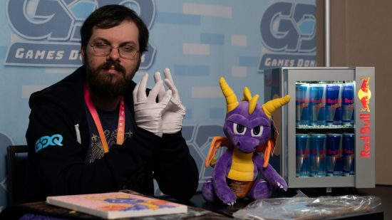 SGDQ 2023 - a person wearing white gloves steeples their fingers, while a Spyro the Dragon plushie sits nearby.