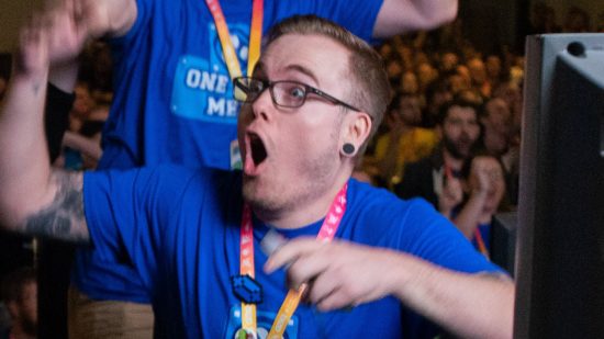 SGDQ 2023 - a speedrunner wearing a blue shirt celebrates excitedly with their teammates in front of a large crowd.