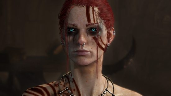Diablo 4 ground effects changes - a red-haired Necromancer with piercing blue eyes and runes painted on their skin in blood.