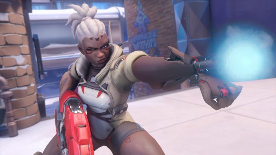 Overwatch 2 characters: a woman with a robotic arm fires the gun that is protruding from her wrist.