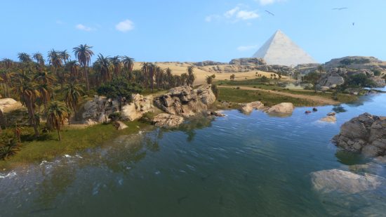 The river nile with a pyramid in the distance and a clear blue sky overhead.