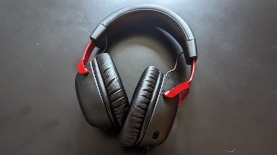HyperX Cloud 3 in review: An overhead view of a black and red headset on a black table with strong overhead lighting.