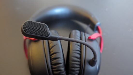 HyperX Cloud 3 review: A black and red headset sits on a black table, with the microphone in perfect focus near the camera.
