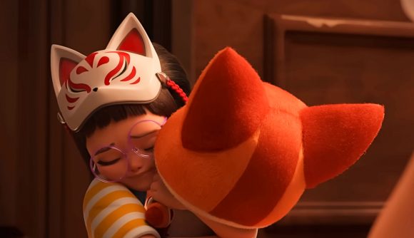 A little girl wearing a white and red fox mask hugs a fox plush toy
