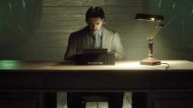 A man is sitting at a desk, typing on his typewriter, waiting for the Alan Wake 2 release date.