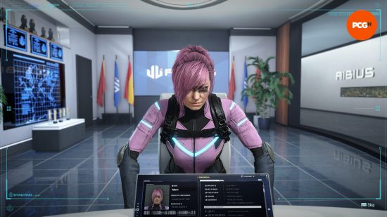 A woman with pink hair tied back wearing a skin-tight pink and blue jumpsuit leaning onto a table in front of a screen profiling her