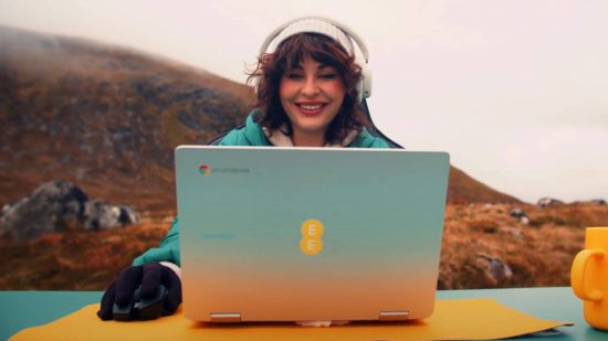 Nvidia GeForce Now EE cloud gaming: a woman in hat and gloves uses a computer with a mountain backdrop.