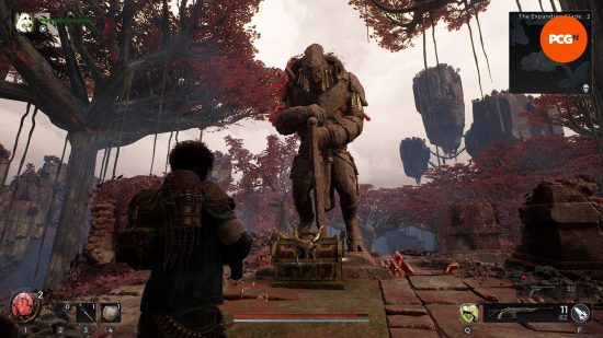 Remnant 2 review: A Traveler approaches a statue of a faun-like being holding a greathammer with a loot chest at its feet.