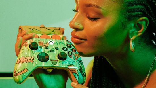 An image of a model holding one of the TMNT controllers, smelling the pizza-shaped diffuser on the back of it.