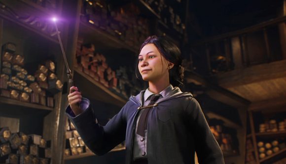 A young witch holds a glowing purple wand in front of her face