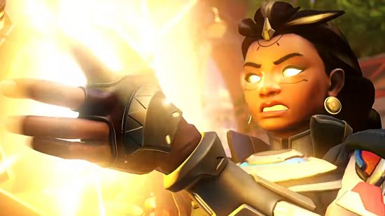 Overwatch 2 Invasion's new support hero, Illari, stands with glowing yellow eyes and an orb of glowing power before her
