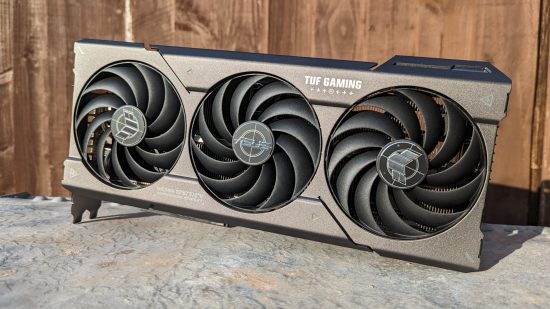 AMD Radeon RX 7700 XT review: The ASUS TUF Gaming model of the graphics card rests atop a metal surface with a wood backdrop