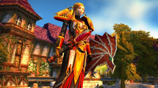 There are WoW Classic systems Blizzard "wouldn't want to bring back": A cartoon woman with blond hair tied back holding a huge staff with a red gem wearing gold and red robes stands in front of a quaint house as the sun splits the skies