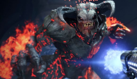 Doom Eternal Denuvo: A large demonic creature with grey skin and horns on its head snarls, fire spreading behind him