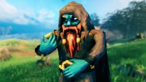 Valheim update: a teal-colored dward with a long red beard stands against a grassy backdrop wearing a hooded cloak