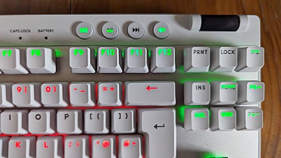 Logitech G Pro X TKL Lightspeed review: the top right of a white keyboard with red and green RGB lighting is shown above a wooden worktop.