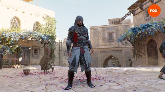 Basim is wearing his Assassin's Creed Valhalla costume over the top of his AC Mirage outfits. He is standing in a street filled with rose petals as a man looks the other way.
