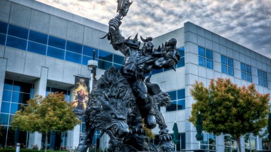 A huge black statue of an orc sitting on a snarling wolf in front of a white and blue office building