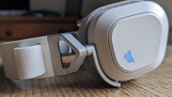 Corsair HS80 Max review: a white headset with retracted microphone appears side-on on a wooden table.