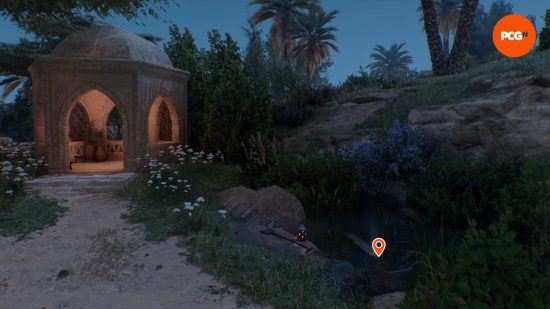 AC Mirage treasure: a glowing pile of treasure in a pond next to a small building.