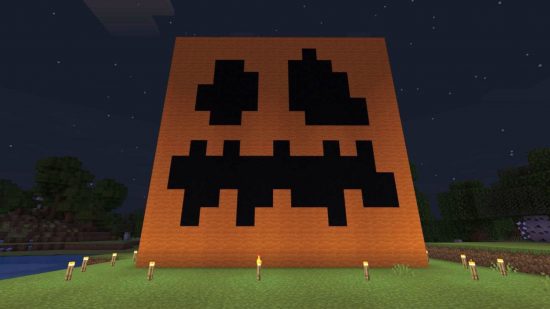 Minecraft best halloween builds: a pumpkin built in Minecraft, with torches around the bottom of it as it is night time